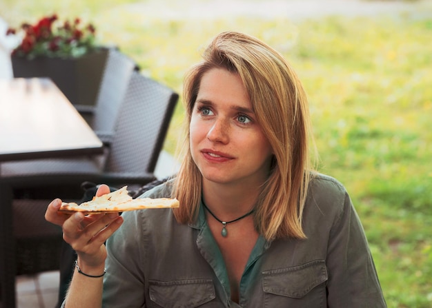 Young woman eating pizza in a street cafe