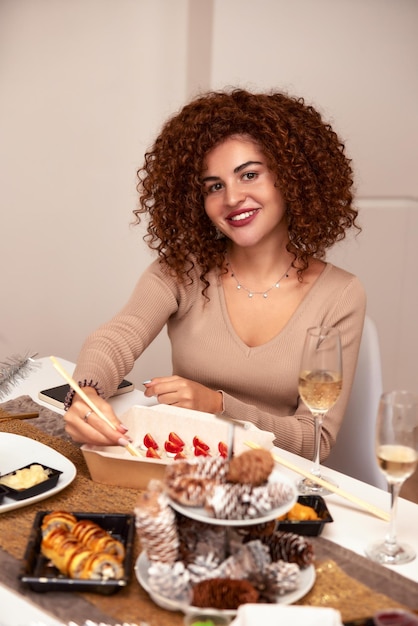 Young woman eating sushi asian food and noodles using choopsticks from take away delivery