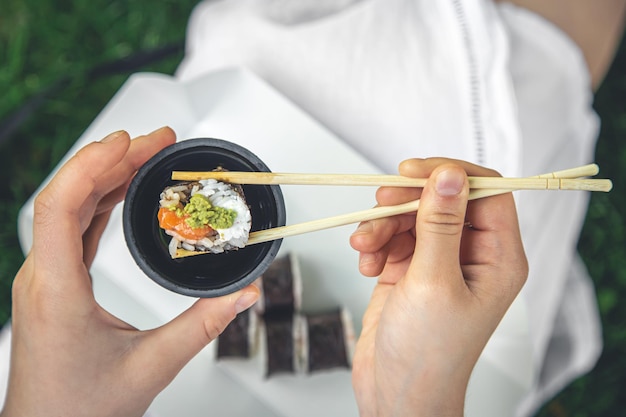 A young woman eating sushi in nature maki roll closeup