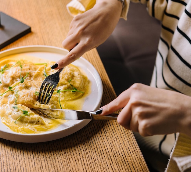 Young woman eating tasty ravioli in cafe