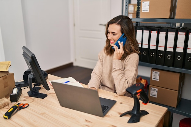 Young woman ecommerce business worker talking on the smartphone working at office