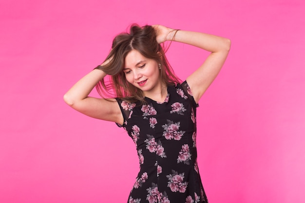 Young woman in elegant summer dress. Girl posing on a pink background.