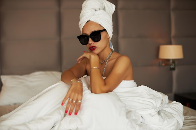 Young woman in elegant sunglasses with a towel around her hair high quality photo