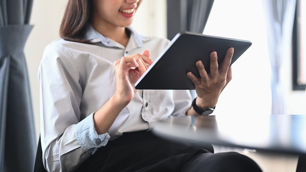 Young woman employee sitting in office and using digital tablet.