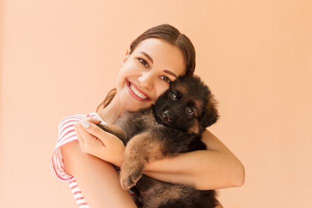 Young woman enjoys hugging a small cute puppy