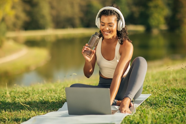 Photo young woman enjoys online learning while sitting by the lake