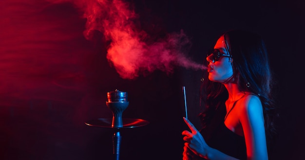 Young woman enjoys smoking a hookah