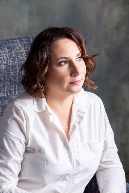 Young woman of European appearance in a white shirt posing. Portrait, close-up.