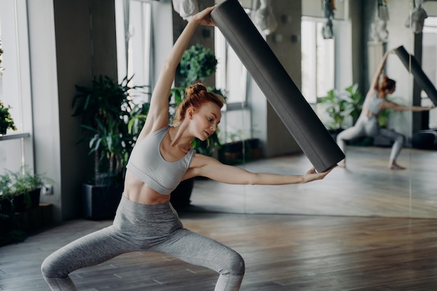 Young woman exercising with pilates foam roller in half sitting position