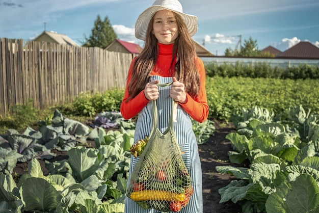 Young woman farmer agronomist collects fresh vegetables in the garden Organic raw products grown on a home farm