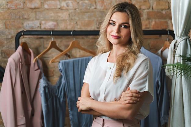 Photo young woman fashion designer and clothing rack with different outfits