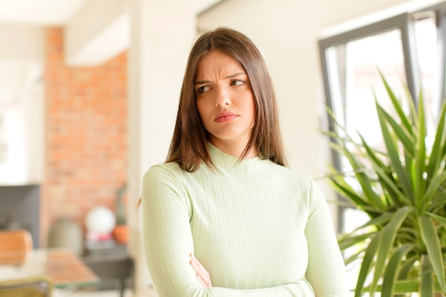 Young woman feeling sad upset or angry and looking to the side with a negative attitude frowning in disagreement