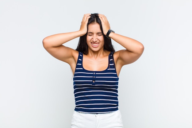 Young woman feeling stressed and frustrated, raising hands to head, feeling tired, unhappy and with migraine