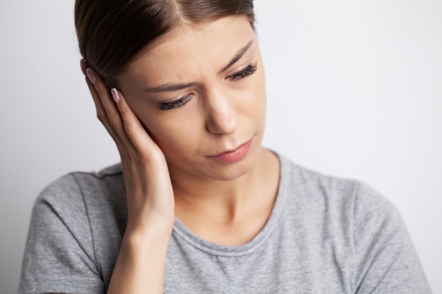 A young woman feels a headache and holds the place of pain with her hands