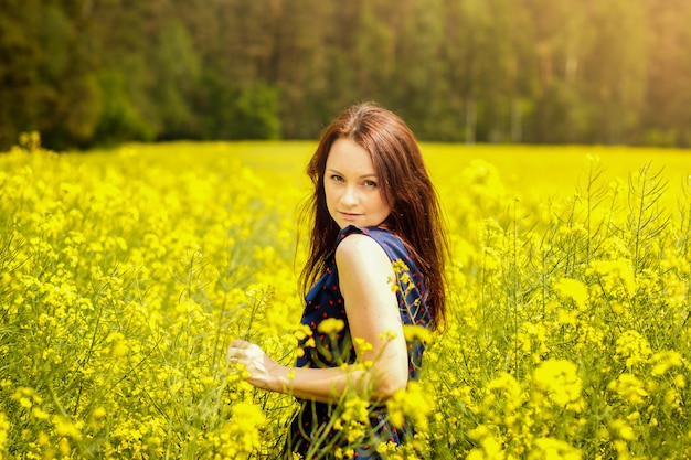 young woman in a field of rapeseed on a sunny day