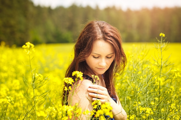 young woman in a field of rapeseed on a sunny day