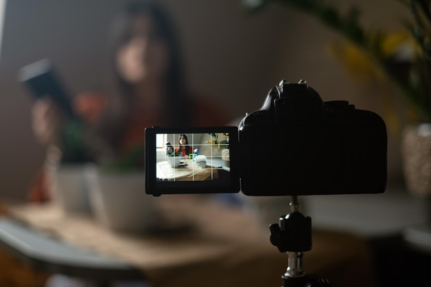 Photo a young woman films a video blog and happily plants bright flowers