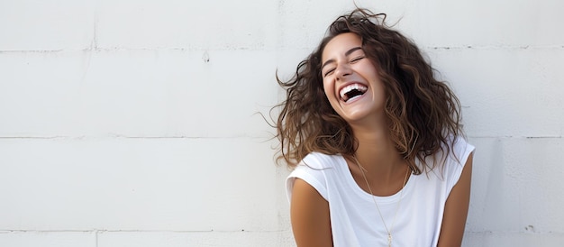 A young woman finds something amusing and leans against a white wall