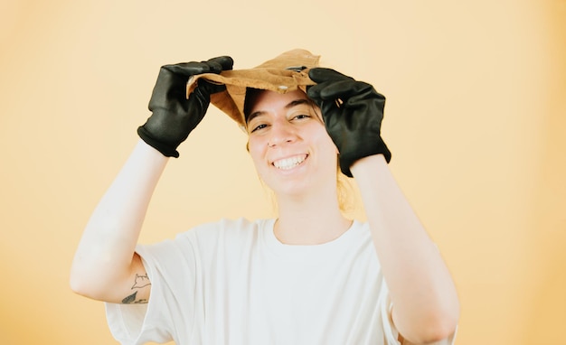 Young woman finishing at work as tin welderHappy with the job done and thrilledWelding helmets and protective glovesOrange backgroundNew generationsCarefulprudent and cautious