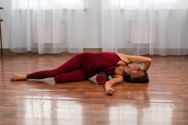 A young woman fitness instructor in red sportswear leggings and top stretching in the gym before her