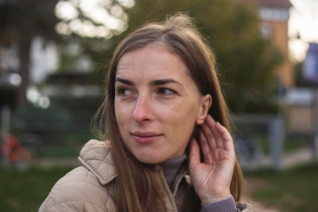 Young woman fixing her hair in a jacket on the street