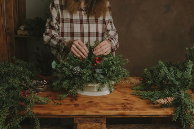 Young woman florist creating Christmas flower arrangement in flower shop studio