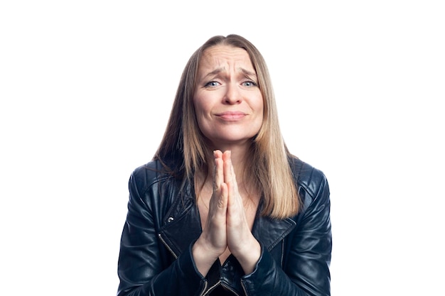 The young woman folded her hands in supplication Pretty woman in a black leather jacket Faith energy and fulfillment of desires Isolated on white background