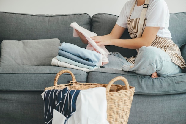 Young woman folding clothes on sofa at home