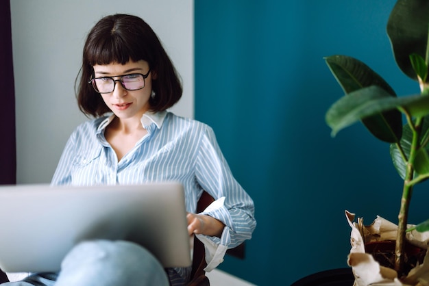 Young woman freelancer sit on modern sofa and work on laptop Education online Working from home