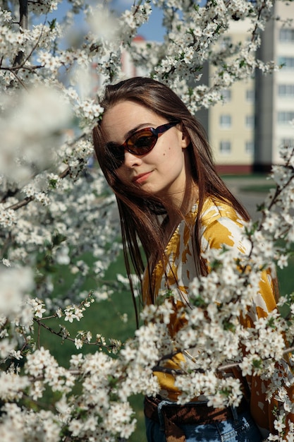 Young woman in garden with blooming trees in spring