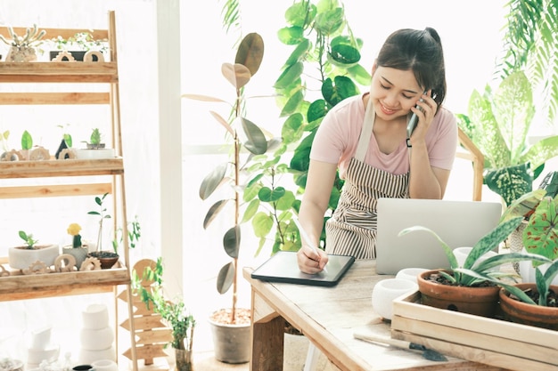 Young woman gardener is standing in the garden to contact customers