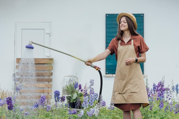 Young woman gardener watering garden plants