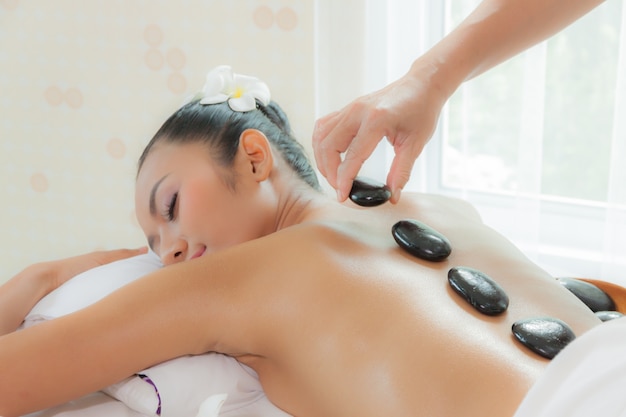 Young woman getting hot stone massage in spa salon