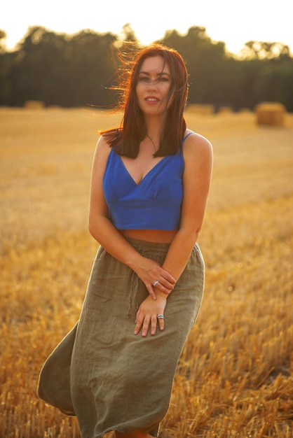 a young woman or girl in a field with wheat walks at sunset