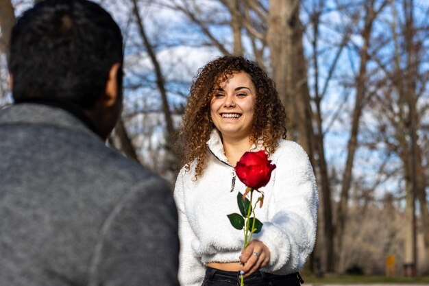 Young woman giving a red rose to her boyfriend