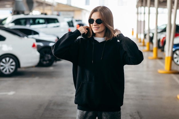 Young woman in glasses and black hoodie