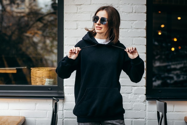 Young woman in glasses and black hoodie