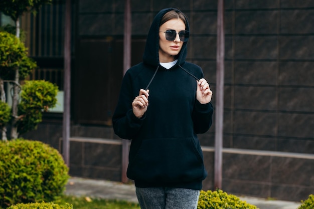 Young woman in glasses and black hoodie