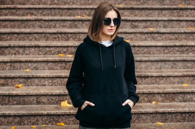 Young woman in glasses and black hoodie