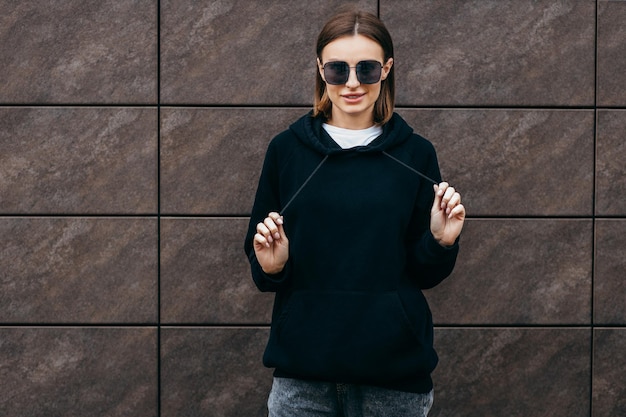 Young woman in glasses and black hoodie