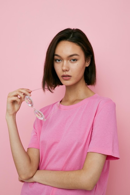 Young woman glasses in the form of diamonds in a pink tshirt pink background