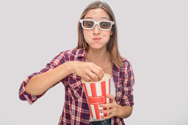 Young woman in glasses standing and watching straight.