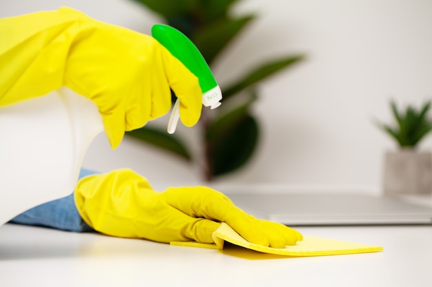 Young woman in gloves cleaning office table