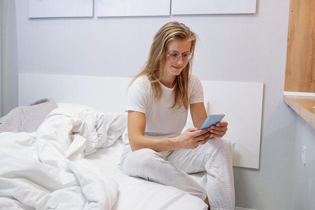 young woman going to bed at night and using her smartphone