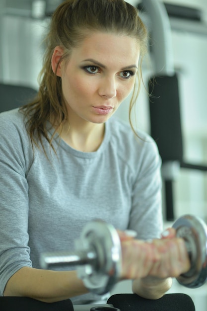 Young woman in a gym with a dumbbell