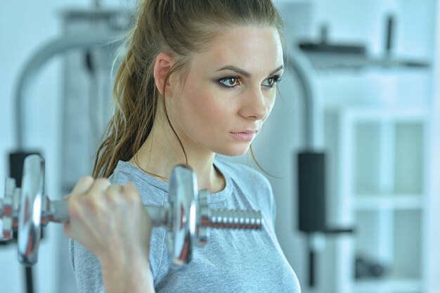 Young woman in a gym with a dumbbell