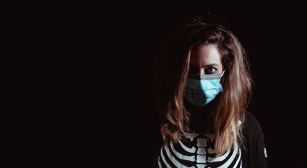 Young woman in halloween skeleton costume with surgical mask Night of the dead Copy space