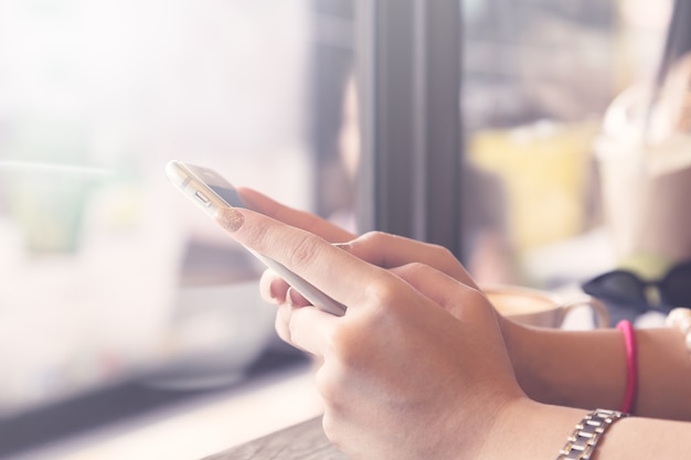 Young woman hand holding using smartphone for social online in coffee shop