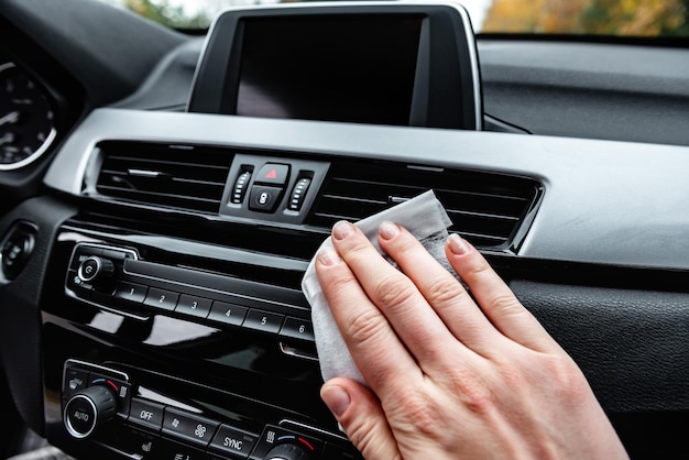 Young woman hands cleaning dust of car by white wet cloth.