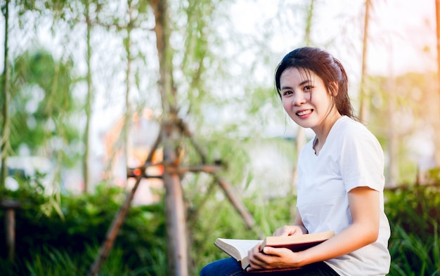 Young woman happily reading the book in nature